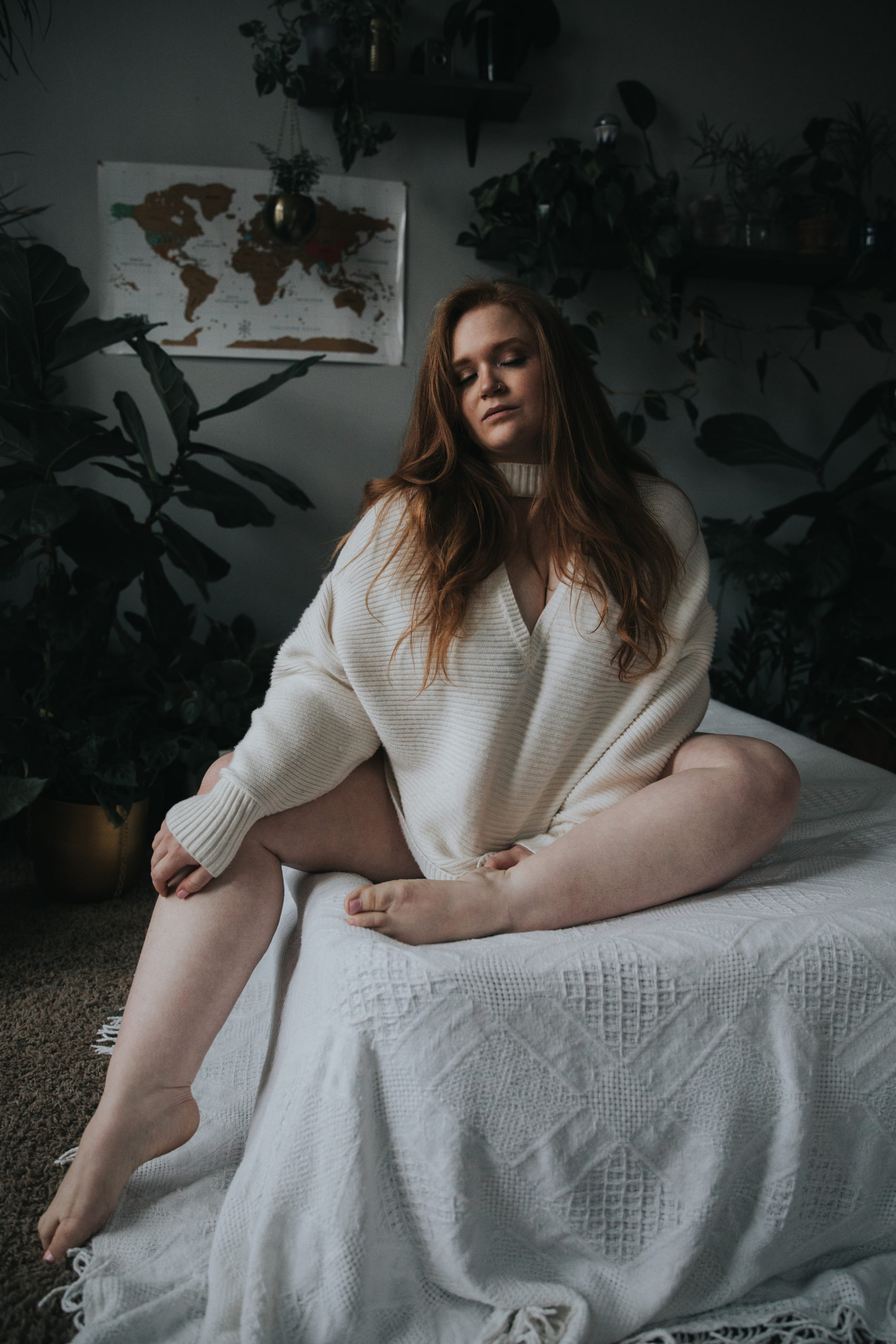 Red head woman wearing a white sweater for moody boudoir photos