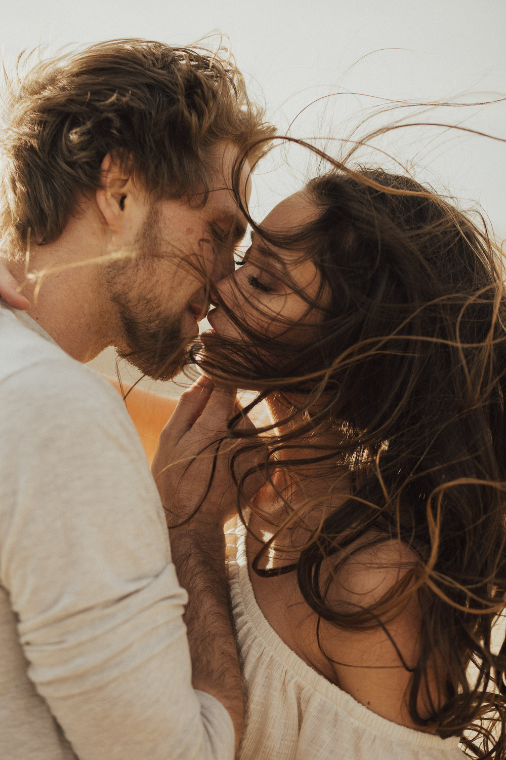 Couple kissing in high winds. Her hair falling perfectly as shes kissed gently