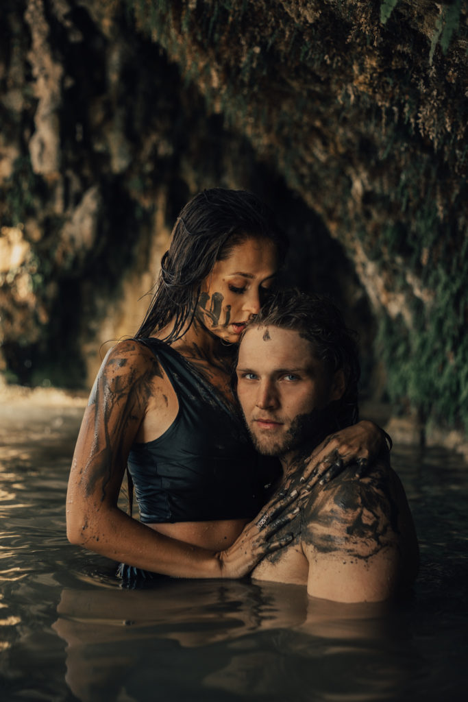 Man and woman holding each other while covered in mud. 