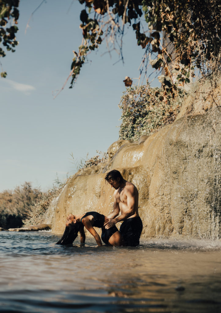 Woman arching back into the water while her husband holds her waist