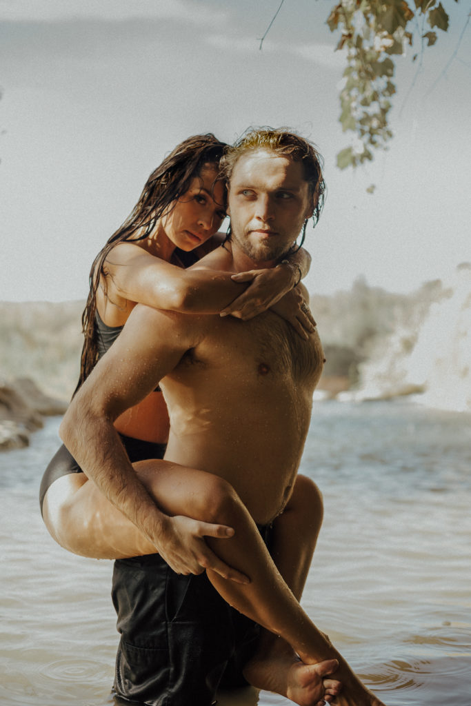 Man giving a woman a piggyback ride during boudoir session