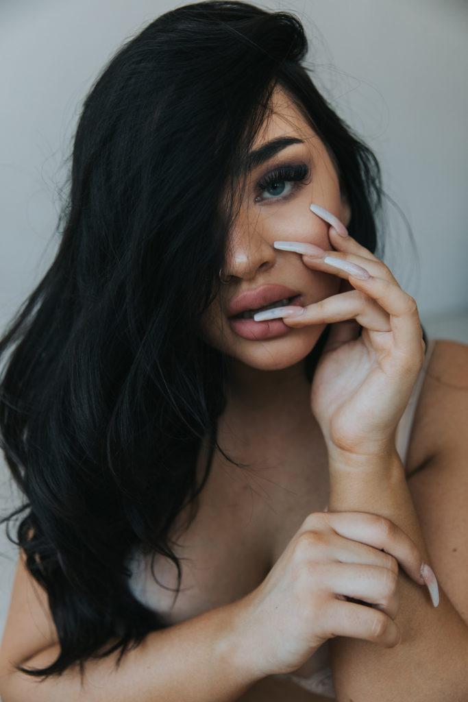Closeup photo of a woman with her hair flipped and a finger in her mouth as a sexy pose