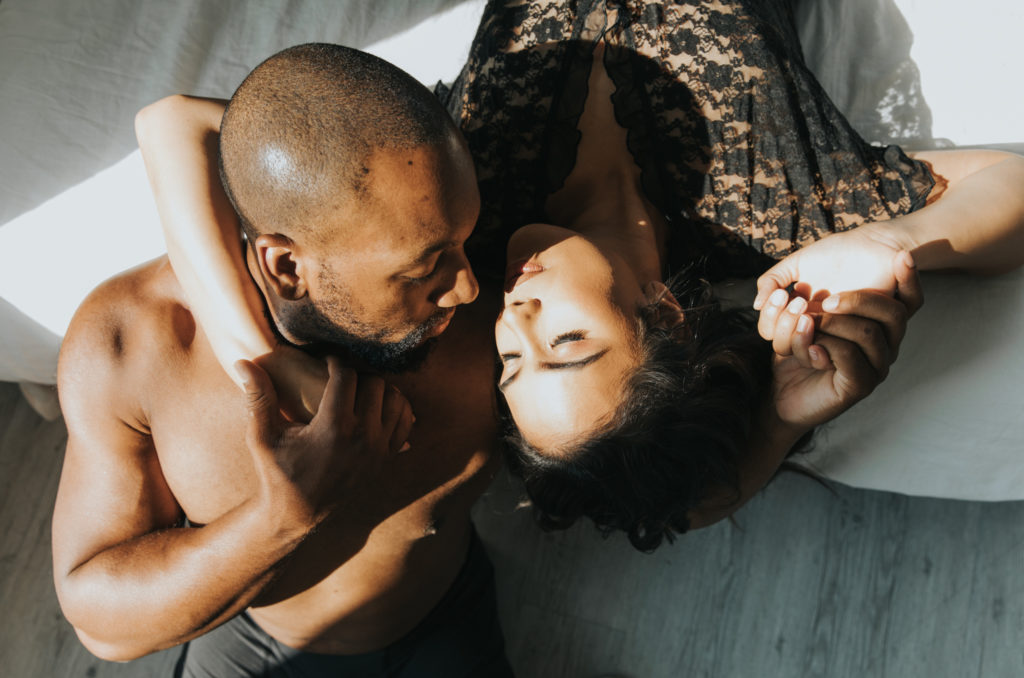 Couple laying on the floor in the sunlight during boudoir session. 