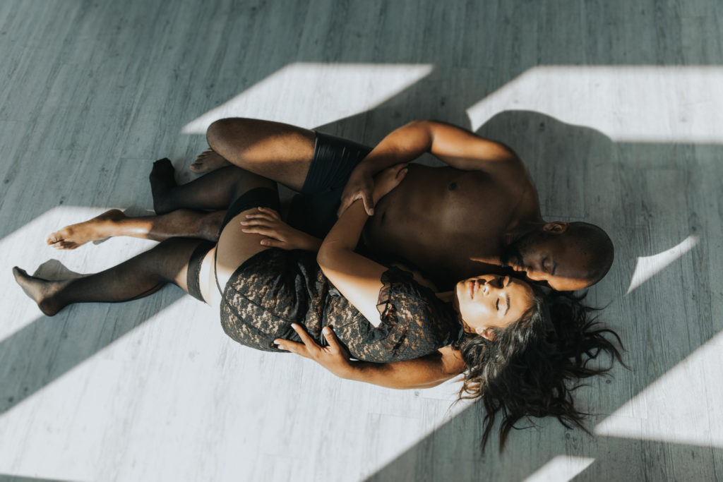 Couple lying on the floor, holding each other during couples boudoir session