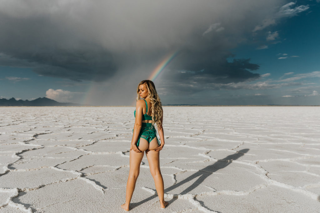 woman standing on the salt flats with stormy skies and a rainbow