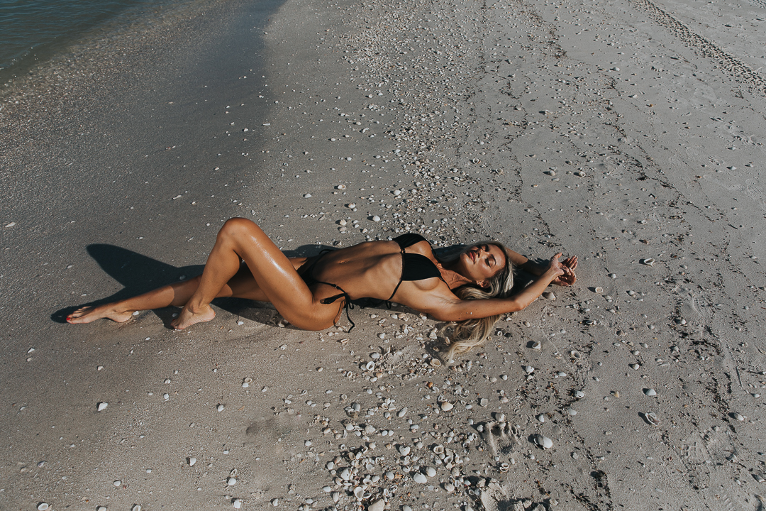 Woman laying on the sand at the beach during photoshoot